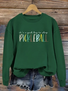 Close-up of 'it's a good day to play pickleball' print on a dark green sweatshirt