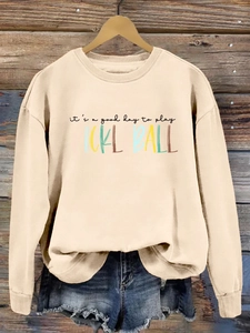 Detail of a beige pickleball sweatshirt with colorful slogan on a vintage wooden background