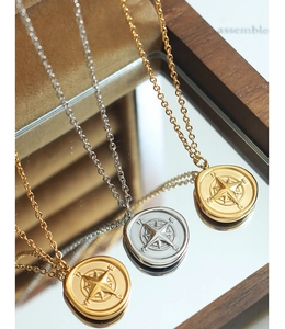 Vue détaillée du pendentif boussole doré et argenté avec gravure des points cardinaux