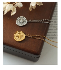 Détail de colliers avec pendentif boussole or et argent sur une boîte à bijoux vintage