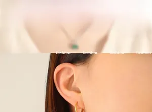 Close-up of golden hoop earrings and necklace with emerald green square zircon pendant