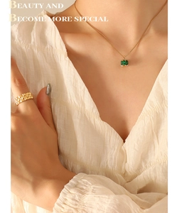Close-up of gold necklace with emerald zircon and chain texture ring on model