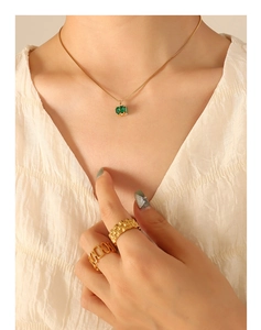 Detail of emerald zircon pendant necklace and gold rings set worn by a model