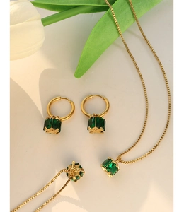 Close-up of emerald green zircon jewelry set with gold four-prong square pendants