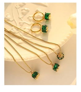 Detail of emerald zircon necklace and hoop earrings on an elegant porcelain plate