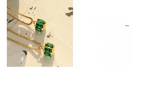Detailed close-up of emerald zircon pendant with four-claw gold-plated chain necklace