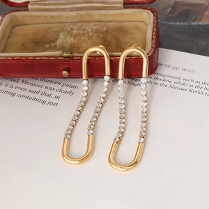 Boucles d'oreilles dorées en U avec zircons sur fond de boîte rouge vintage