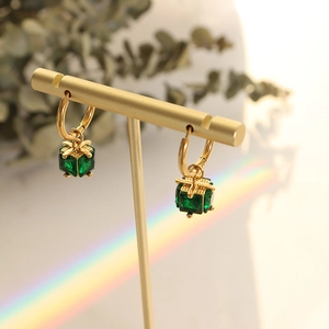 Elegant emerald gift box earrings with golden bow accents on a jewelry display stand