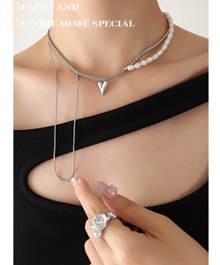 Détail du collier de perles d'eau douce avec pendentif cœur et bague ouverte