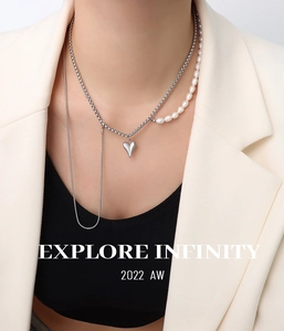Détail d'un collier multicouche avec perles d'eau douce, chaîne argentée et pendentif cœur