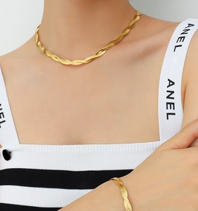 Detail view of twisted gold-plated snake chain necklace and bracelet on model