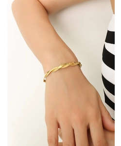 Detail of twisted gold rope chain bracelet featuring a multi-strand woven texture and shine