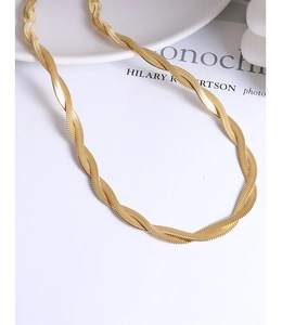 Close-up of golden dual-strand twisted herringbone chain necklace on aesthetic background