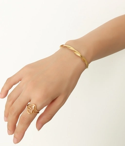 Detail of twisted rope chain bracelet and minimalist face outline ring in 18k gold finish