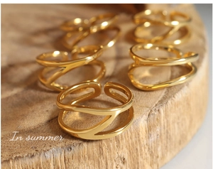 Detail of hollow double-layer crisscross gold rings placed on a natural wood surface