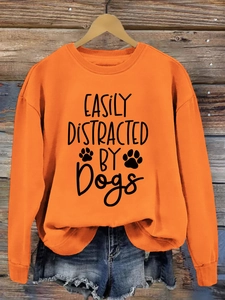 Detail of Easily Distracted by Dogs slogan and paw prints on orange pullover sweatshirt