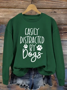 Detail of Easily Distracted by Dogs print on dark green crewneck sweatshirt flat lay