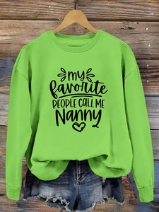 Détail d'un sweat vert avec imprimé 'My Favorite People' sur un mur en bois