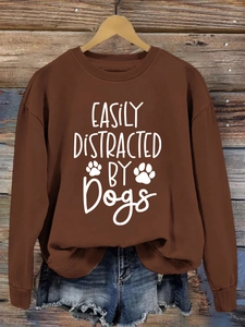 Detail of white Dogs slogan and paw prints on a brown long-sleeve cotton sweatshirt