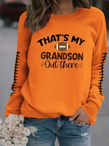 Détail d'un sweat orange avec imprimé football et coutures décoratives sur les manches