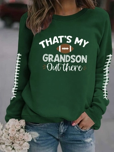Détail d'un sweat vert foncé avec imprimé football et motif sur les manches