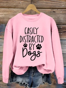 Close-up of pink crewneck sweatshirt featuring easily distracted by dogs letter print