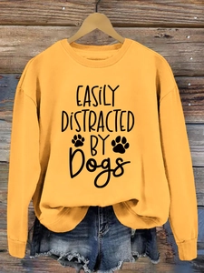 Detail of yellow sweatshirt with EASILY DISTRACTED BY Dogs print on wood background