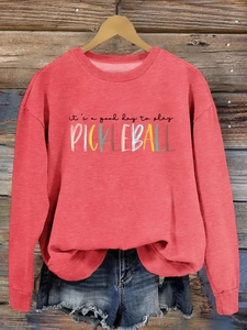 Close-up of pink Pickleball sweatshirt with colorful letter print on vintage wood