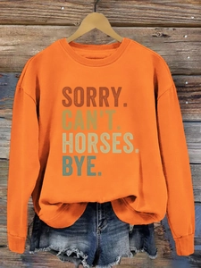 Détail des poignets côtelés et du texte dégradé rétro sur le sweat orange à col rond