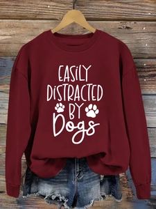 Detail of burgundy sweatshirt with white Easily Distracted by Dogs print on wooden hanger