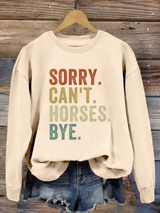 Gros plan de l'imprimé vintage 'SORRY CAN'T HORSES' sur le sweat à col rond crème