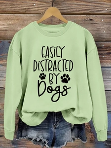 Close-up of light green sweatshirt featuring easily distracted by dogs graphic print