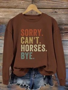 Détail de l'imprimé vintage Sorry Can't Horses Bye sur un sweatshirt marron à manches