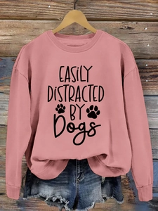Detail of pink sweatshirt with easily distracted by dogs print on wooden background