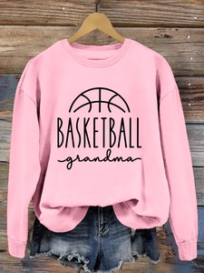 Detail view of pink Basketball Grandma sweatshirt on a wooden hanger with denim shorts