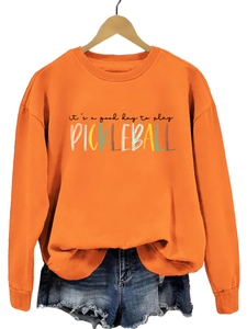 Detail of orange pickleball sweatshirt showing the vibrant graphic print and ribbed crewneck
