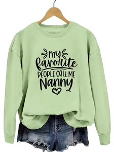 Détail d'un sweat vert clair avec imprimé cœur Nanny sur un cintre en bois