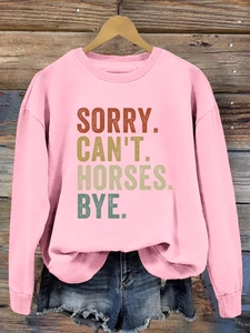 Détail du sweat rose à col rond avec imprimé rétro SORRY CAN'T HORSES sur fond en bois rustique