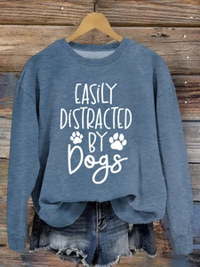 Close-up of blue crewneck sweatshirt with Easily Distracted by Dogs slogan and paw prints