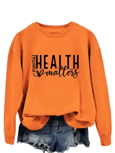 Detail view of mental health matters slogan printed on an orange crewneck sweatshirt