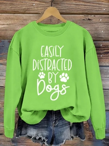 Detail of green crewneck sweatshirt with white 'Easily Distracted By Dogs' print and ribbing