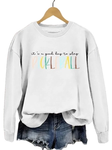 Close-up of Pickleball graphic print on a white crewneck sweatshirt with denim shorts