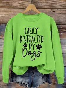 Detail of green crewneck sweatshirt with black 'Easily Distracted by Dogs' print