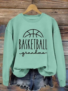 Detail of mint green crewneck sweatshirt featuring Basketball Grandma print on wood