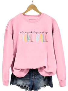 Detailed view of pink pickleball sweatshirt with graphic text on a wooden hanger