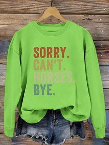 Détail de l'imprimé SORRY CAN'T HORSES sur un sweat-shirt vert et short en jean bleu