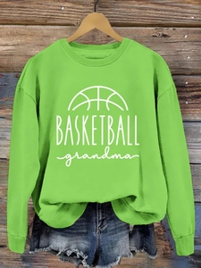Detail of green crewneck sweatshirt with white Basketball Grandma print on a wooden wall