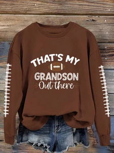 Détail d'un sweat de football marron foncé avec texte blanc et motif de rugby sur bois