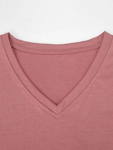 Detailopname van de V-hals met versterkte dubbele stiksels op dit roze katoenen shirt