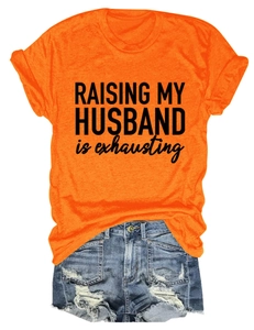 Détail d'un t-shirt orange avec imprimé Raising My Husband et short en jean bleu à trous